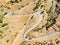 Aerial view of serpentine road snaking between mountains in West Greece. A road full of twists and turns winding sharply up the