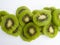 Aerial view of several slices of green kiwis on a white background