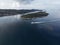 Aerial view of a ship driving on the sea with a small forested island