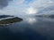 Aerial view of a ship driving on the sea with a small forested island