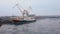 Aerial view of shipbuilding yard with huge cargo crane and old rusty vessel standing on water with melting ice and floes