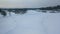 Aerial view of ski track and ski lodges near the forest in winter against grey evening sky. Footage. Sports and