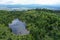 Aerial view of small blind mountain lake reflecting dense clouds, surrounded by coniferous forest recovering from heavy windstorm.