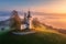 Aerial view of small church on the hill and orange low clouds