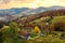 Aerial view of small shepherd houses on wide meadow between autumn forest in Ukrainian Carpathian mountains at sunset