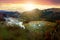 Aerial view of small shepherd houses on wide meadow between autumn forest in Ukrainian Carpathian mountains at sunset