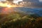 Aerial view of small shepherd houses on wide meadow between autumn forest in Ukrainian Carpathian mountains at sunset