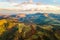 Aerial view of small shepherd houses on wide meadow between autumn forest in Ukrainian Carpathian mountains at sunset