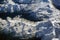 Aerial view of snowy mountains peaks and a winding serpentine, switchback road, opposite the sunlight