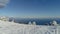 Aerial view of snowy mountains, sea, cloudy sky. Shot. Snow-covered hills by the sea