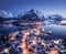 Aerial view of snowy village, city lights, sea, mountain at night