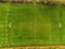 Aerial view, soccer or football field under maintenance, Tractor with feeder and trail all over the pitch