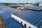 Aerial view of solar power plant with blue photovoltaic panels mounted on industrial building roof for producing green