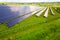 Aerial view of solar power plant on green field with protective wire fence around it. Electric panels for producing clean ecologic