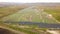 Aerial view of solar power plant under construction on green field. Assembling of electric panels for producing clean