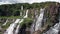 Aerial view of spectacular waterfall cascades flowing on rocky cliff in jungle.