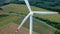 Aerial view on spinning blades of wind turbine tower on wheat field