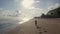 Aerial view sportsman runs alone on sandy beach, ocean and sunset on background