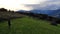 Aerial view of sporty man running at perfect green grass rural meadow with dramatic sky in mountains