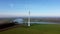 Aerial view of a stationary wind turbine on a river in a Dutch landscape.