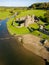 Aerial view of stepping stones over a small river leading to the ruins of an ancient castle Ogmore Castle, Wales