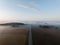 Aerial view of a straight country road and vast farmland on a foggy day