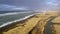 Aerial view of street near ocean, aerial view of a beautiful landscape in Iceland, a small house in the distance near the ocean an