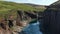 Aerial view of Studlagil Canyon with basalt columns and glacier water river between two lava walls. Famous tourist