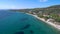 Aerial view of stunning blue beach below a hill in the area of Halkidiki Greece, move forward and down by drone