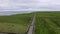 Aerial view summer road: red car travel view, drive. Gorgeous irish fields, nature scene with roadway against Atlantic