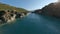 Aerial view sunny mountain landscape flying under walking bridge tourist people river water creek