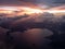 Aerial view of sunset from aircraft window seat. broken cloud overcast the terrain. flying along the coast. rain precipitation fro