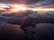 Aerial view of sunset from aircraft window seat. broken cloud overcast the terrain. flying along the coast. rain precipitation fro