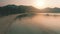 Aerial view sunset over sea mountains with trees, golden hour. Empty boats near sandy colorful shore