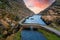 Aerial view of sunset at the stone Wishing Bridge over winding stream in green valley at Gap of Dunloe in Black Valley of Ring of