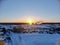 Aerial view of the sunset on a winter freezing evening. Beautiful picturesque landscape of snowy forest and field