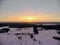 Aerial view of the sunset on a winter freezing evening. Beautiful picturesque landscape of snowy forest and field