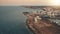 Aerial view, sunshine over blue sea and city on plain. Brown coastline, island summer seascape.