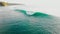 Aerial view of surfers and blue barrel wave in ocean. Surfing and waves