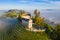 Aerial view of Swiss medieval castle Schloss Schwandegg on a hill with vineyards in a warm sunrise light. A misty foggy valley.