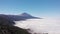 Aerial view - thick clouds cover the valley, pine forest and volcano. Tenerife, Spain