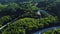 Aerial view of thick forest in autumn with road cutting through