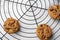 Aerial view of three chocolate cookies on round black rack, on white marble table, selective focus