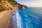 Aerial view to a beach during sunset with golden sunlight and waves breaking the turquoise sea