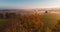 Aerial view to colorful autumn foliage trees with misty fog on meadow and blue sky, Czech landscape, colored photo