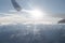 Aerial view to mountains and airplane wing with sunflare