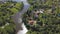 Aerial view of a town with many green trees located along the river in a sunny summer day. Clip. Ecologically clean area