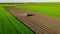 Aerial view of tractor as dragging a sowing machine over agricultural field, farmland