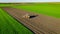 Aerial view of tractor as dragging a sowing machine over agricultural field, farmland