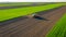 Aerial view of tractor as dragging a sowing machine over agricultural field, farmland